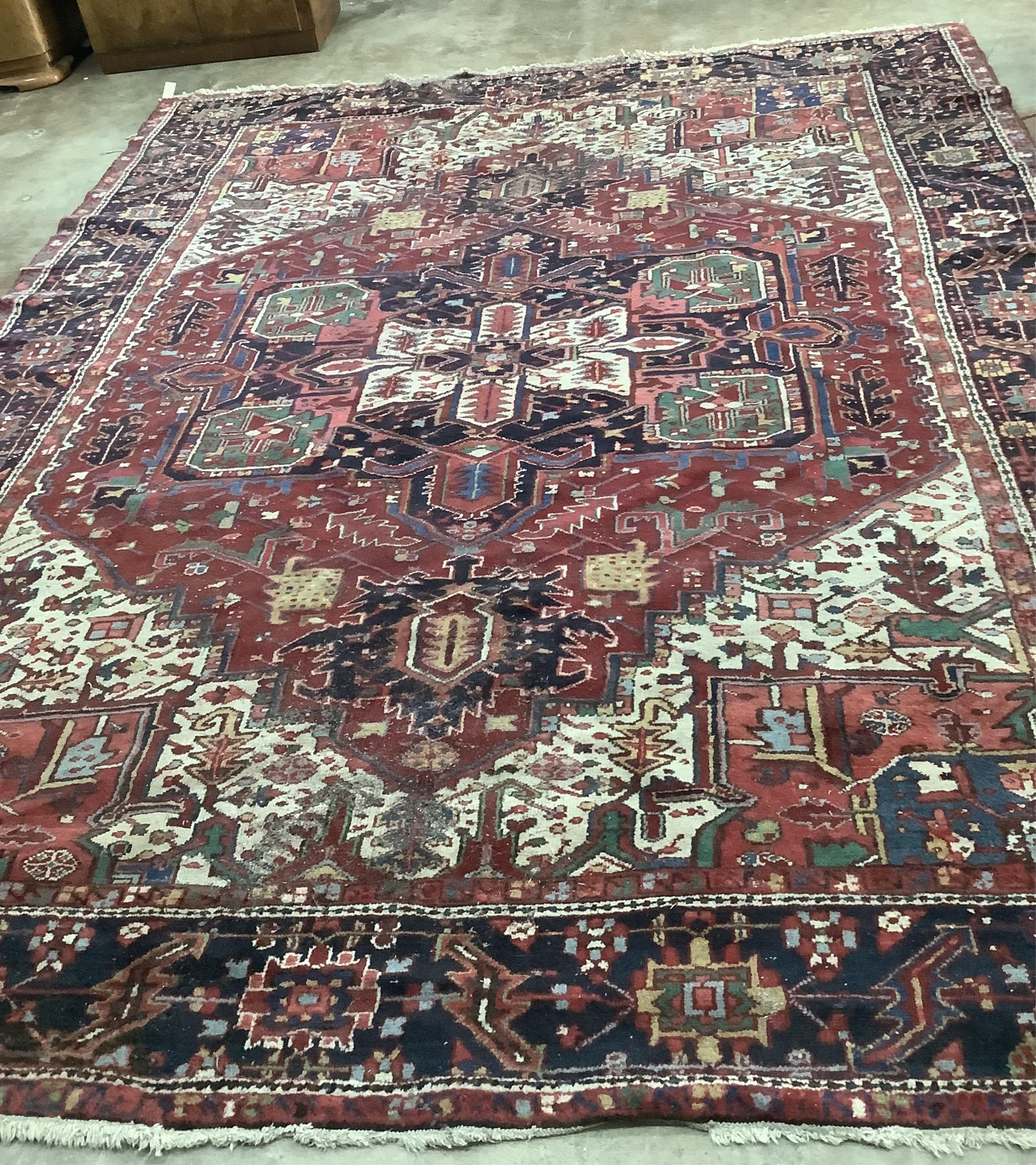 A Heriz red ground carpet, 340 x 267cm. Condition - poor to fair